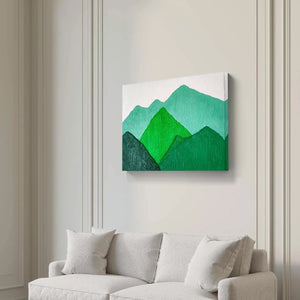 Green mountain landscape painting hung above a white sofa in a minimalist living room.