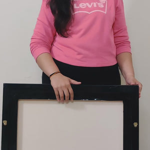 Back view of the framed Lord Shiva canvas held by a person in casual attire.