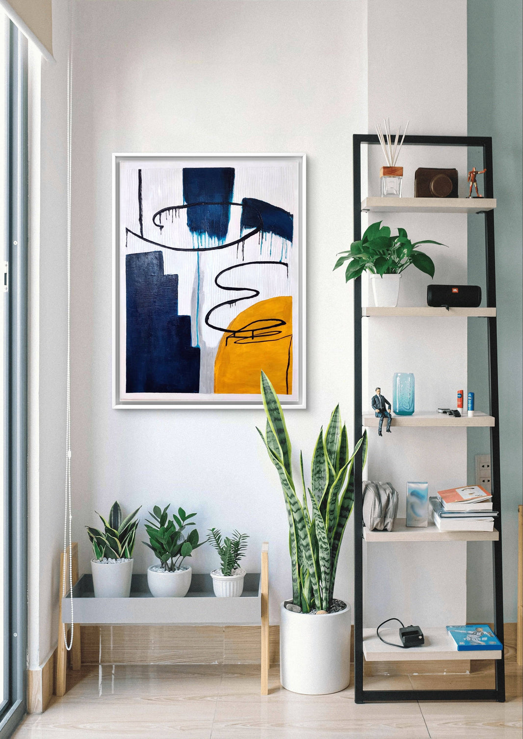 Modern abstract handmade painting with bold blue, yellow, and black textures in a bright living room.