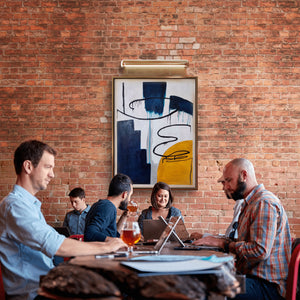Contemporary abstract painting with bold textures hanging in a brick-walled workspace.